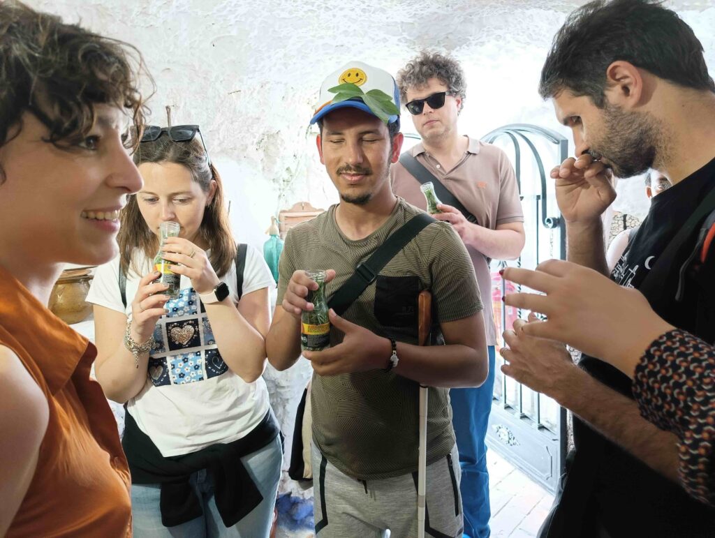 In presenza di una guida locale, alcuni viaggiatori annusano erbe aromatiche da alcune bottigliette in una delle case-grotte di Granada.