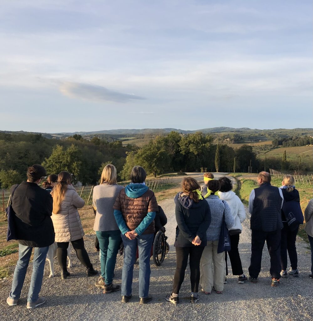 Alcune persone bendate di spalle sono rivolte verso la campagna senese.