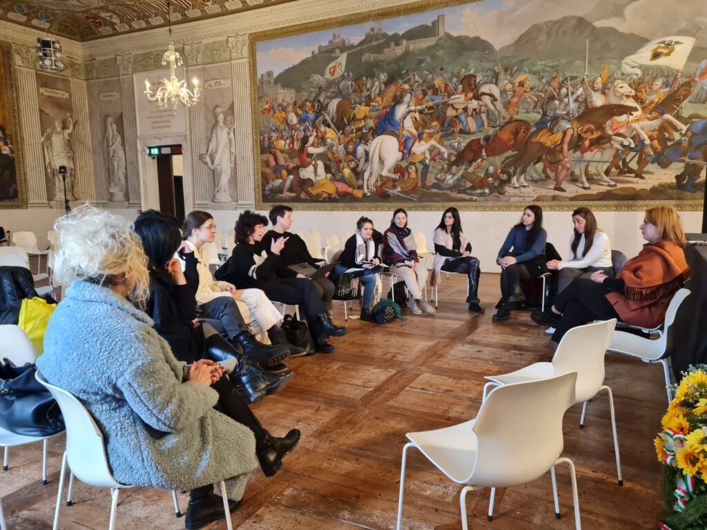 Il gruppo che ha partecipato alla formazione è seduto in cerchio, all'interno di un'elegante sala riccamente affrescata. 